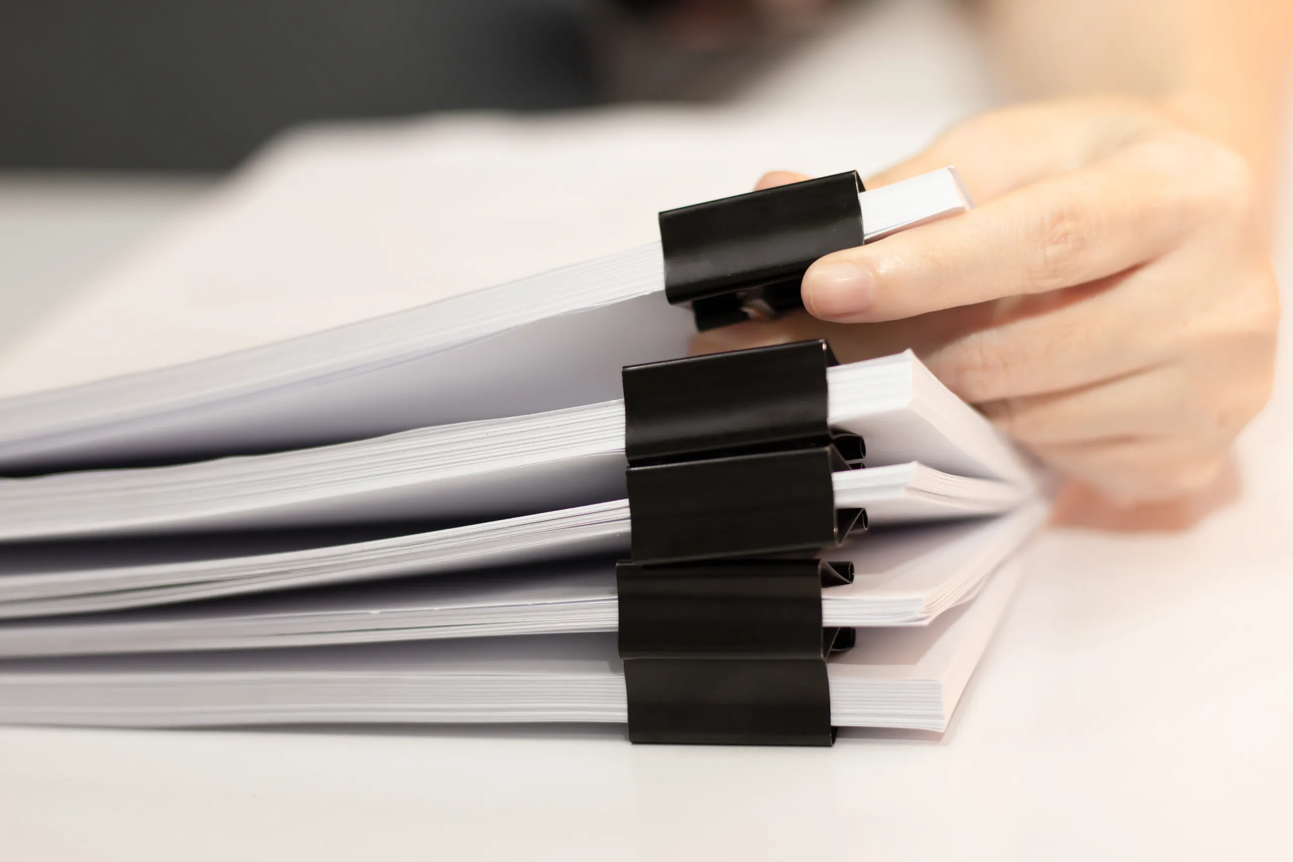 closeup-woman-hand-pick-up-stack-report-papers-document-with-paper-clip-laptop-business-education-concept.jpg